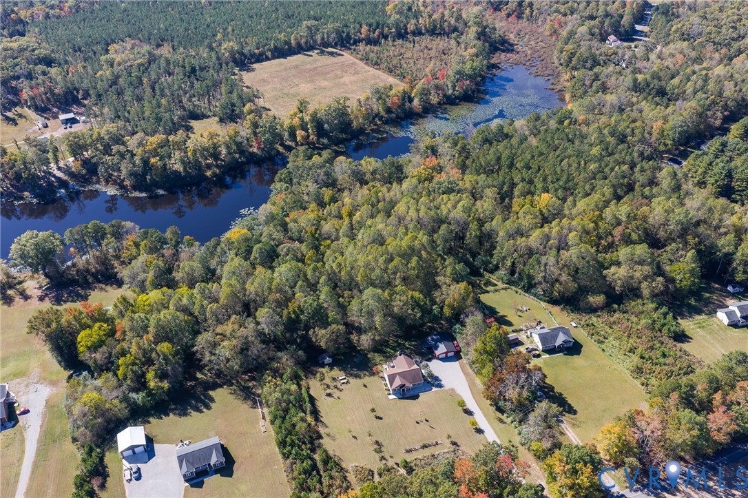 Aerial perspective featuring extensive tree coverage, expansive acreage, and water frontage on a natural pond