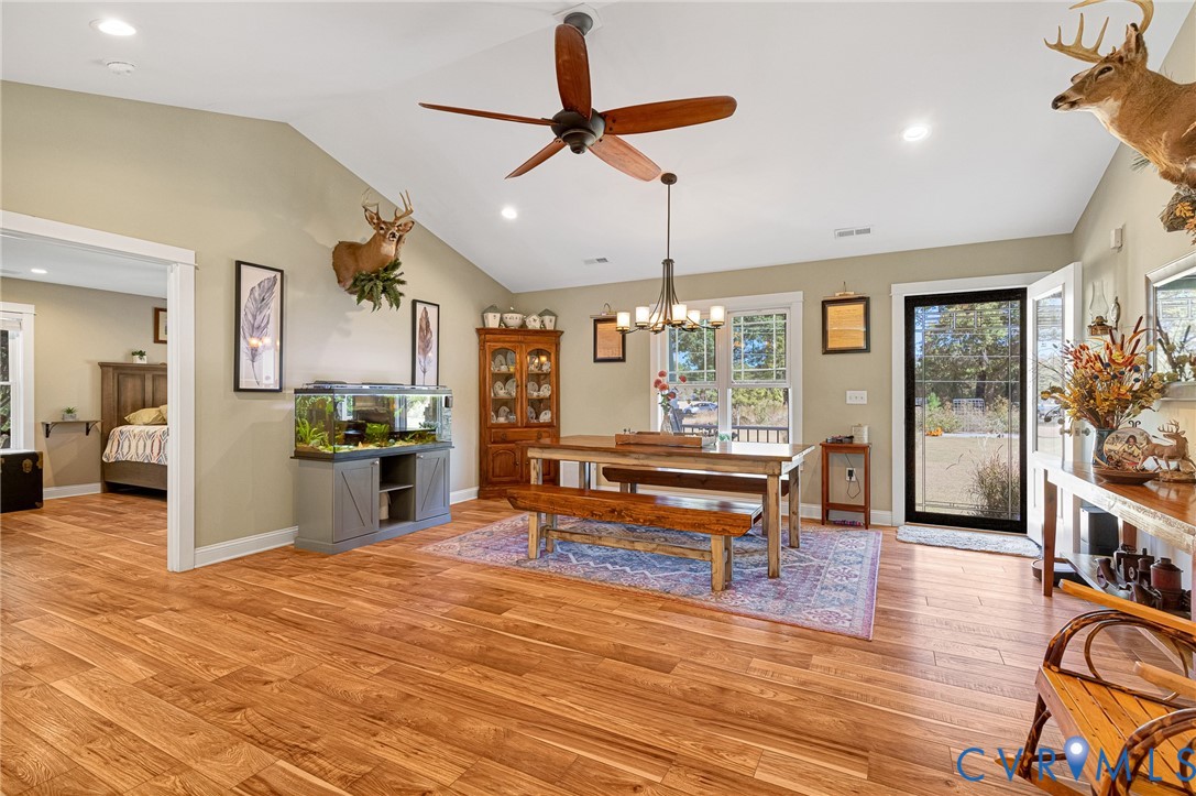 Vaulted ceilings, wood-finish flooring, recessed lighting, multi-arm chandelier, and glass-paned exterior door