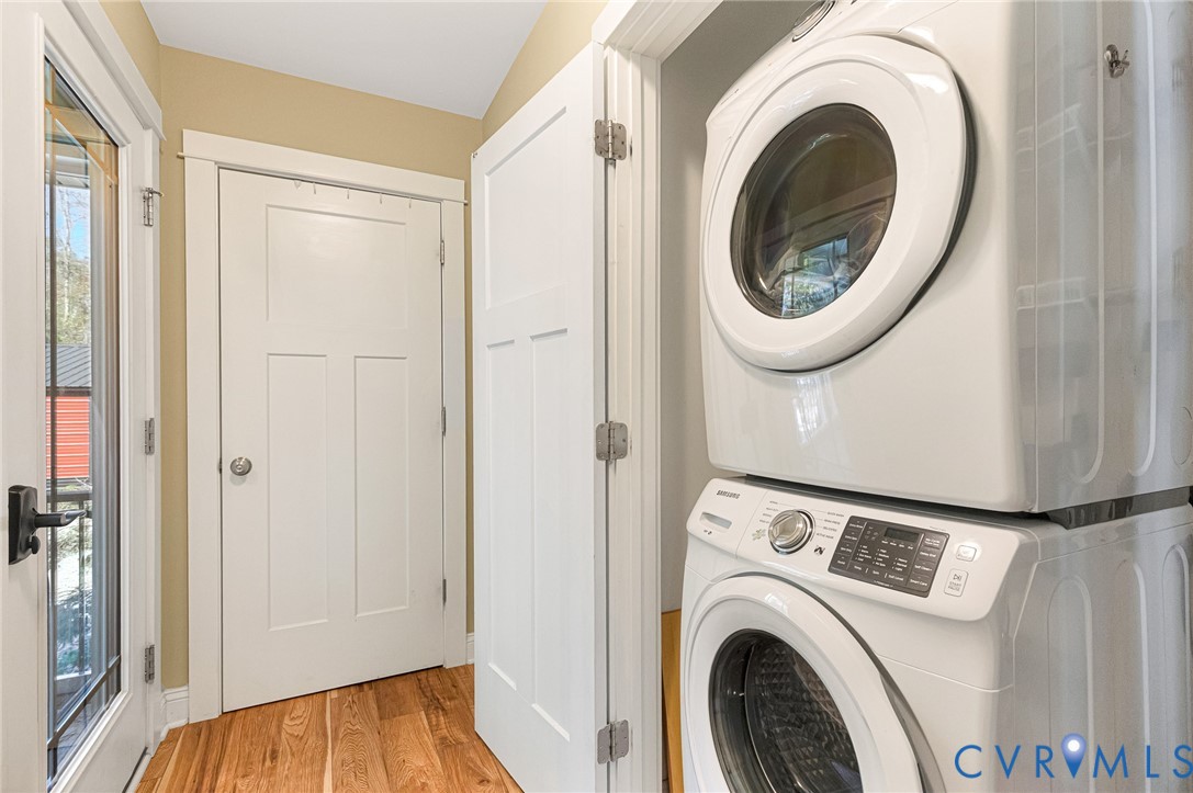 Laundry closet featuring a stackable washer and dryer, wood-finish flooring, and white paneled doors