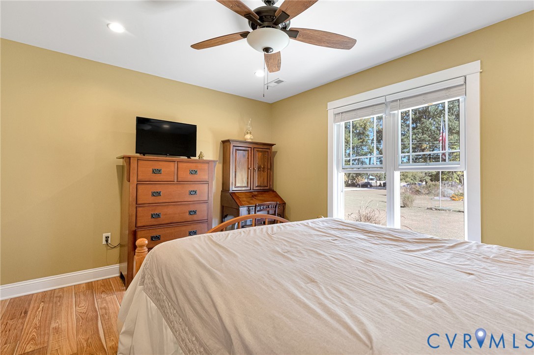 Wood-finish flooring, recessed lighting, ceiling fan with light kit, and multi-pane windows with trim casing
