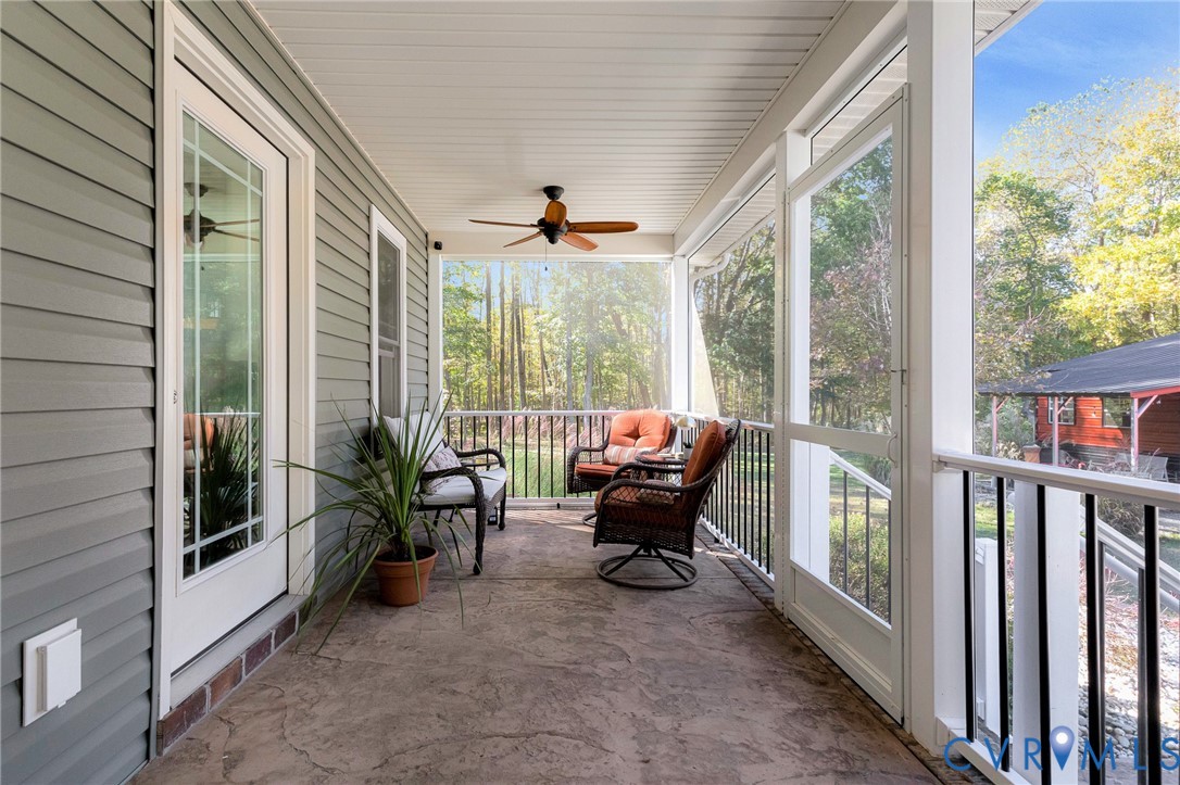 Screened porch featuring a stamped concrete floor, horizontal siding, and a ceiling-mounted fan with light fixture