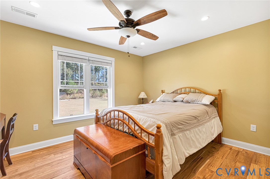 Wood-finish flooring, multi-pane window with wood-trim casing, and ceiling fan with integrated lighting