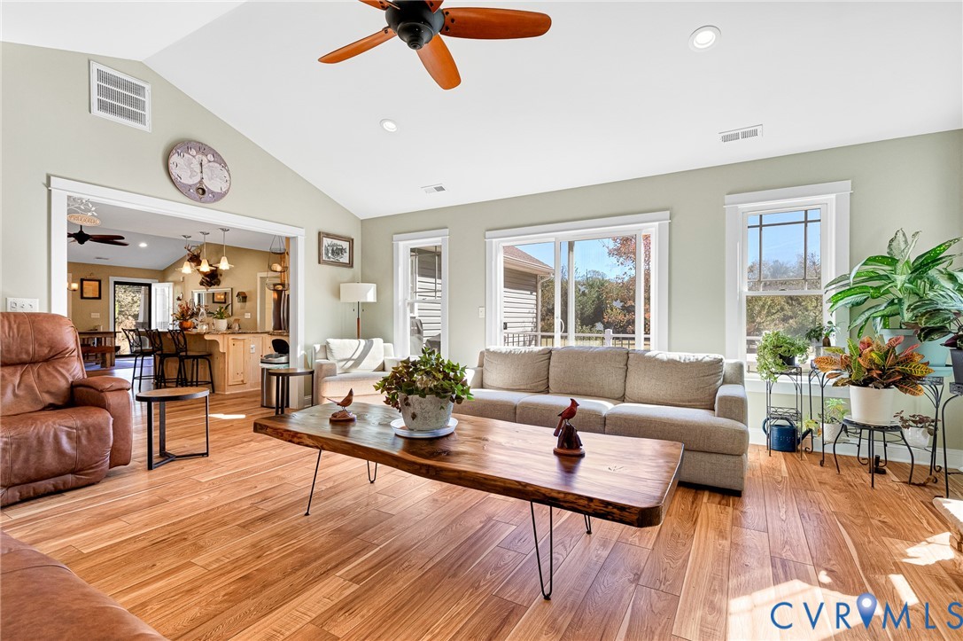 Living area featuring vaulted ceilings, wood-finish flooring, recessed lighting, a ceiling fan, and sliding glass doors