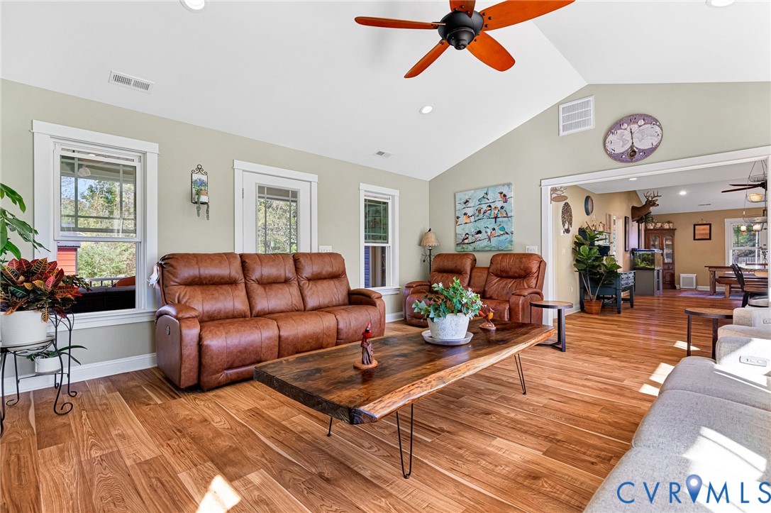 Vaulted ceilings, wood-finish flooring, multi-pane windows, and a ceiling fan with integrated lighting