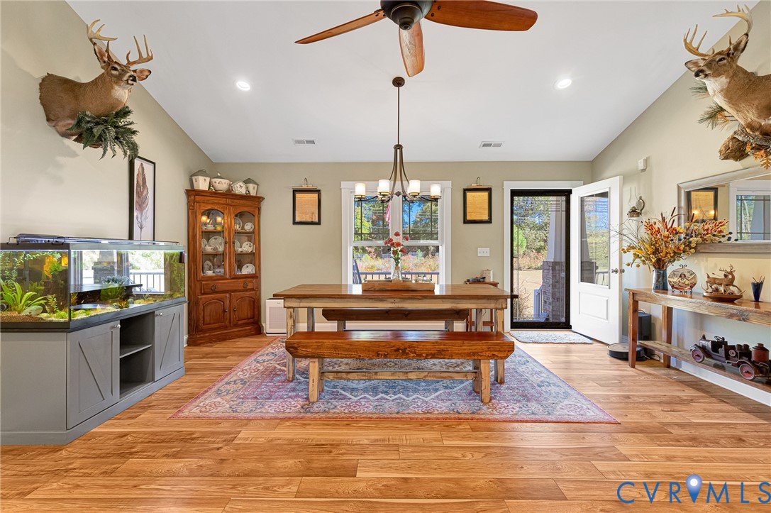 Vaulted ceiling room featuring wood-finish flooring, a central multi-light chandelier, a ceiling fan, and recessed lighting