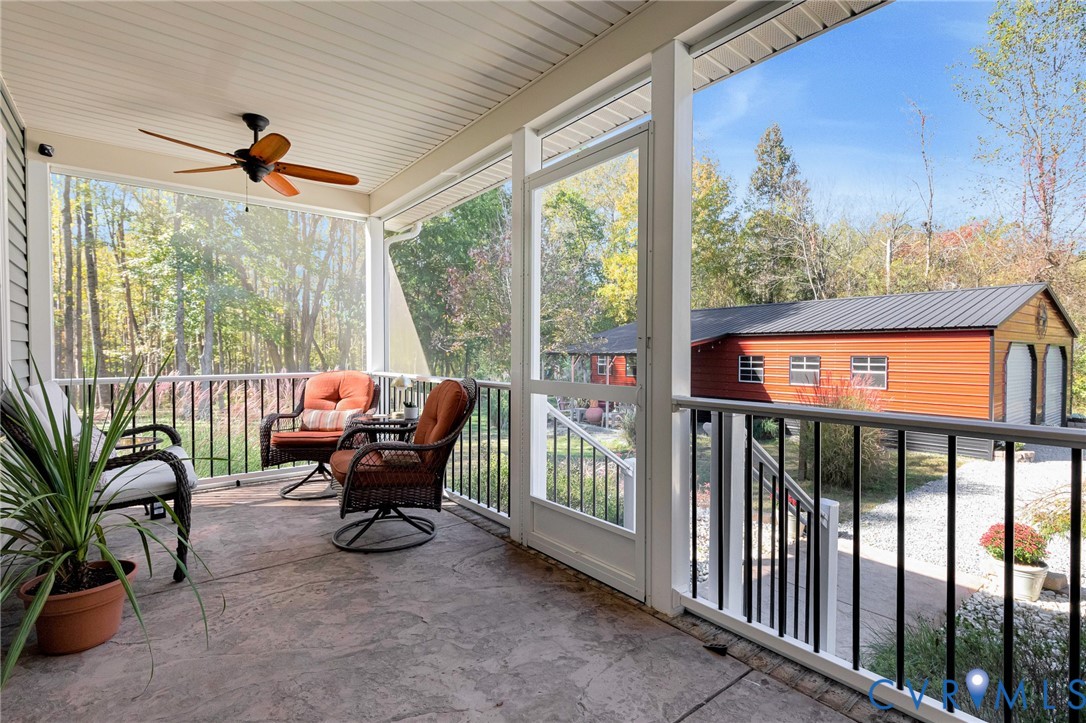 Screened porch featuring concrete flooring, a ceiling fan, and metal railings