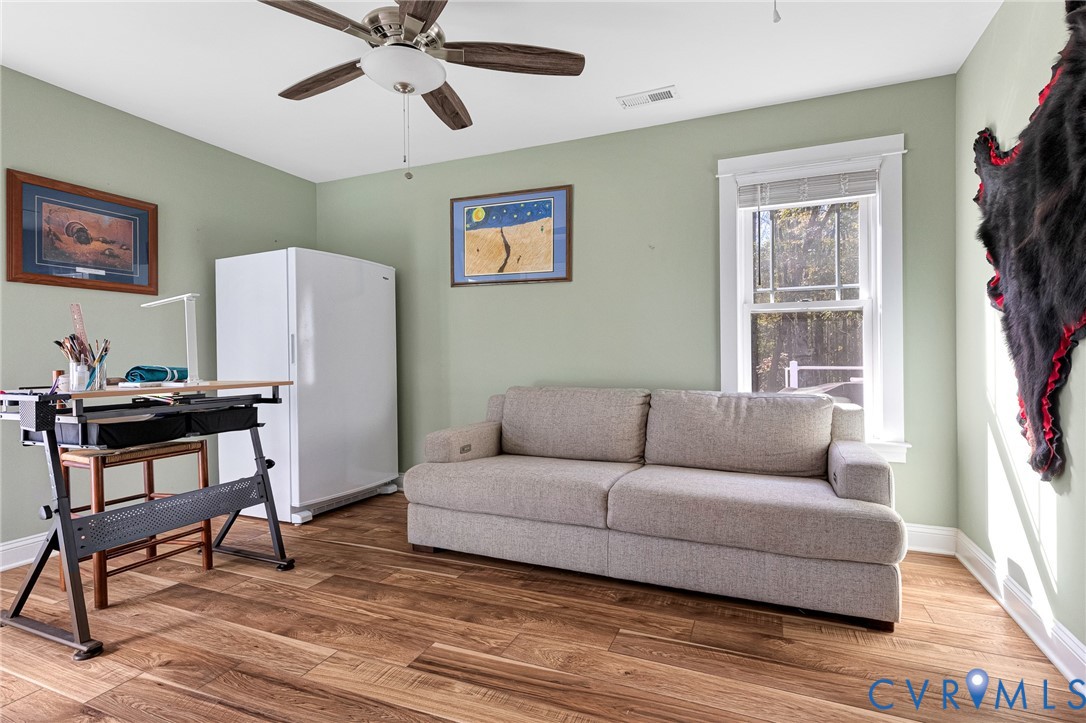 Wood-finish flooring, ceiling fan with integrated lighting, and white-trimmed window