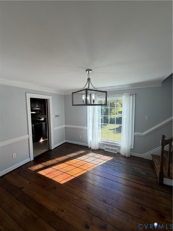 Dining area featuring wood-finish flooring, crown molding, chair rail trim, and a metal-frame geometric chandelier Dining area featuring wood-finish flooring, crown molding, chair rail trim, and a metal-frame geometric chandelier