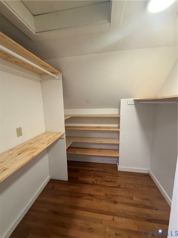 Storage space featuring natural wood-finish shelving, integrated hanging rods, and wood-finish flooring Storage space featuring natural wood-finish shelving, integrated hanging rods, and wood-finish flooring