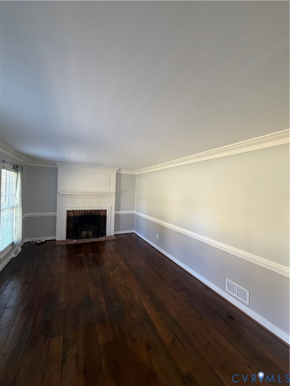Fireplace with a white wood mantel, crown molding, chair rail trim, and dark-toned wood-finish flooring Fireplace with a white wood mantel, crown molding, chair rail trim, and dark-toned wood-finish flooring