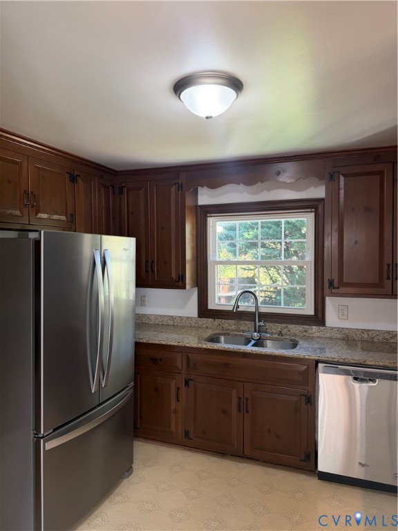 Kitchen featuring stained wood cabinetry, stone-finish countertops, stainless steel appliances, double-basin sink with a pull-down faucet, and a window above the workspace Kitchen featuring stained wood cabinetry, stone-finish countertops, stainless steel appliances, double-basin sink with a pull-down faucet, and a window above the workspace