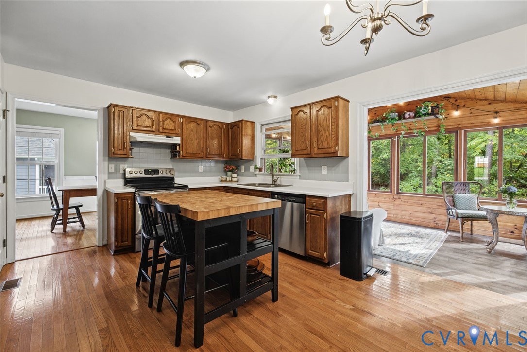 Kitchen featuring wood cabinetry, solid surface countertops, hardwood flooring, and an island with a butcher block top