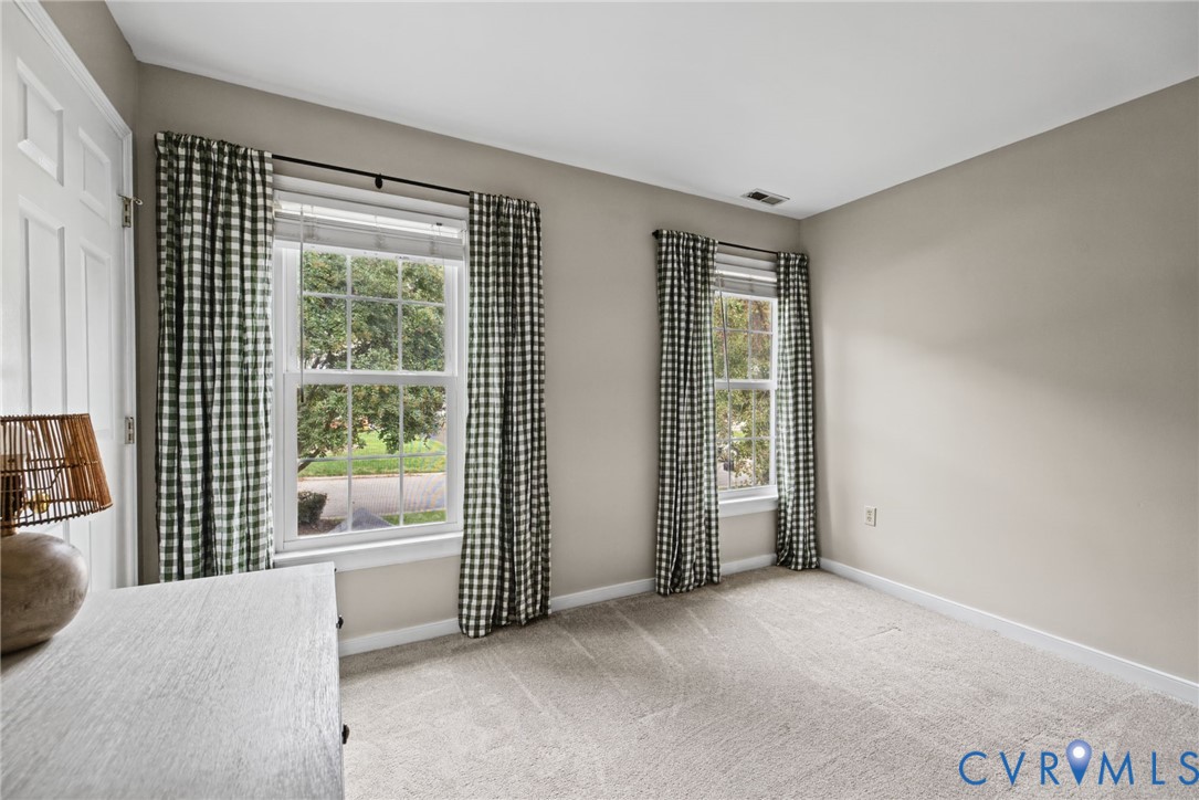 Neutral wall-to-wall carpeting, two double-hung windows with muntins, and paneled interior door
