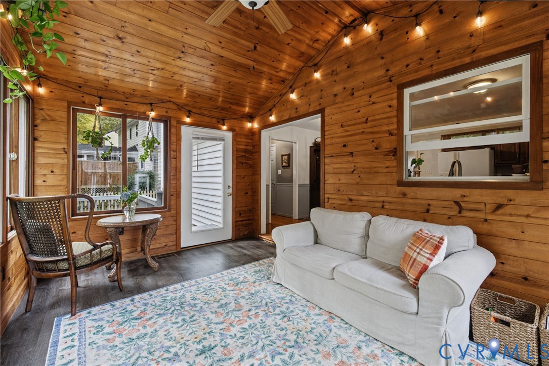 Enclosed sunroom featuring natural wood plank walls and vaulted wood ceilings, vinyl flooring, and a window pass-through