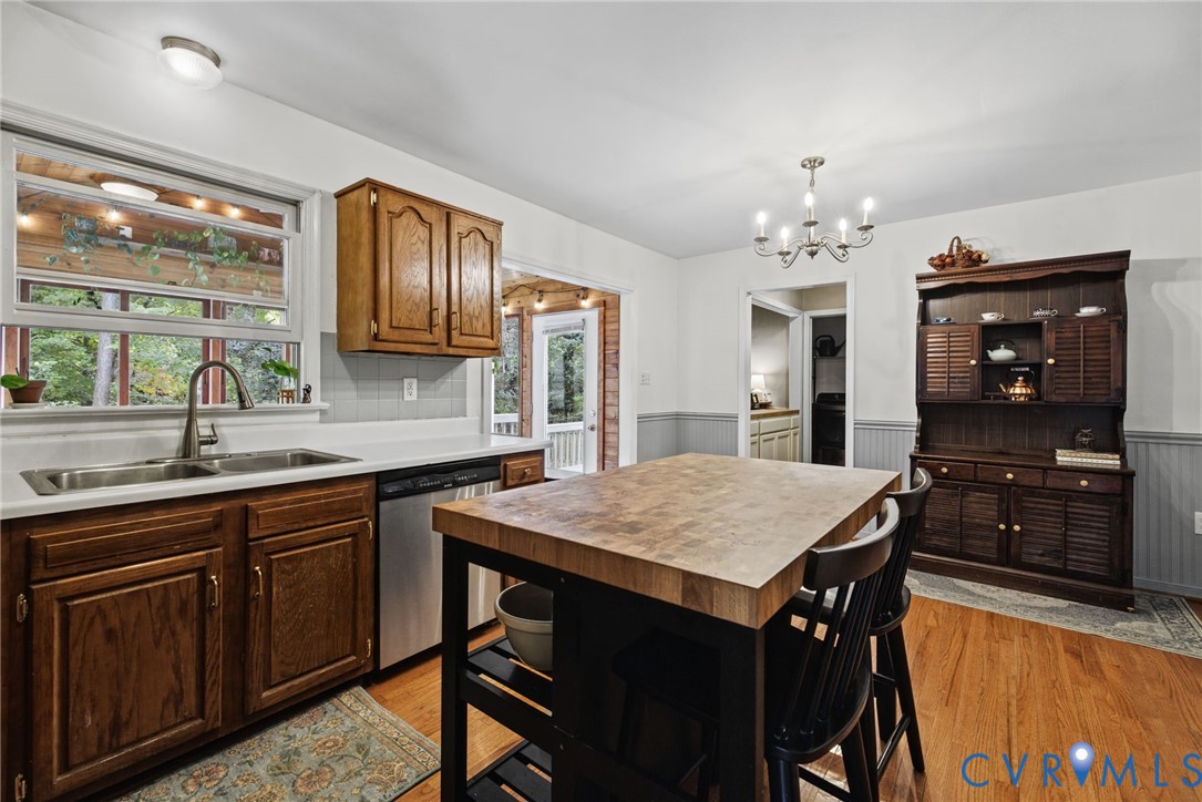 Kitchen featuring wood cabinetry, stainless steel sink with gooseneck faucet, butcher block island, wood-finish flooring, and crown molding detail