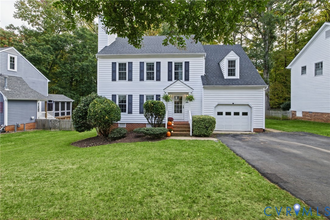 Two-story residence featuring white siding, dark shutters, an attached single-car garage, front dormer window, and an asphalt driveway