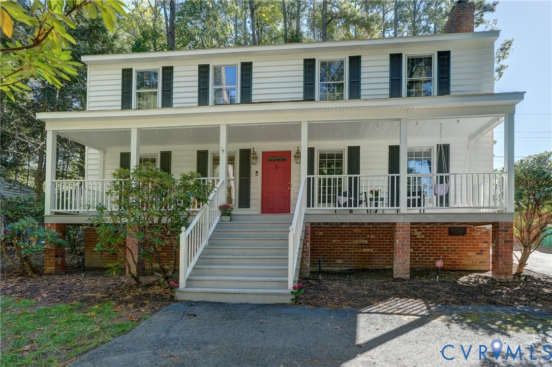 Two-story Colonial exterior featuring white horizontal siding, black shutters, a red front door, and a full-width covered front porch with white railing Two-story Colonial exterior featuring white horizontal siding, black shutters, a red front door, and a full-width covered front porch with white railing