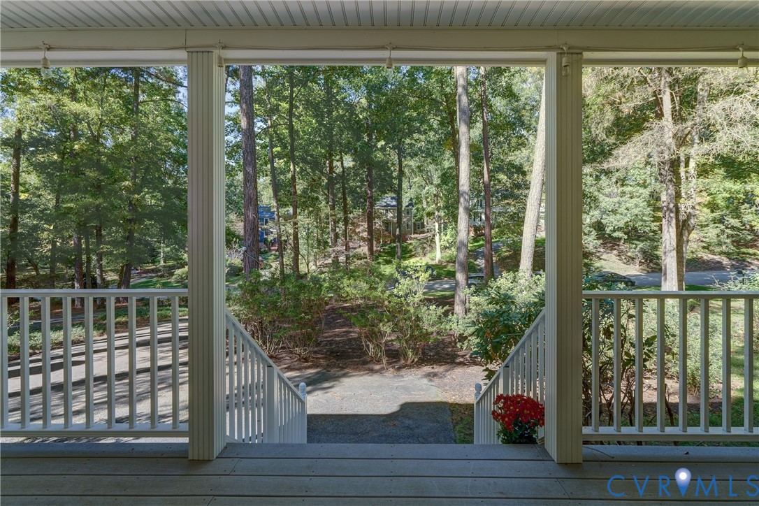 Covered porch featuring painted white balusters, wood-plank flooring, and structural columns Covered porch featuring painted white balusters, wood-plank flooring, and structural columns