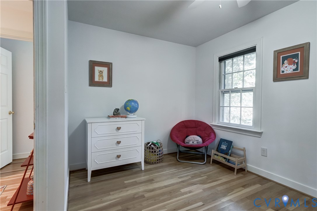 Room featuring wood-finish flooring, a double-hung window, and a ceiling fan