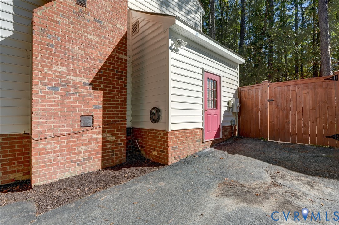 Exterior featuring red brick masonry, horizontal siding, asphalt driveway, and wood-panel privacy fencing