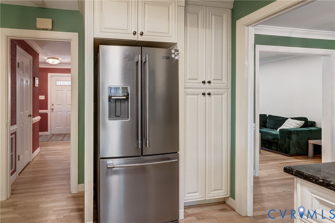 Built-in floor-to-ceiling cabinetry, stainless steel French-door refrigerator, and wood-finish flooring