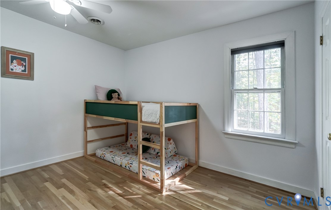 Room featuring wood-finish flooring, a multi-pane window, and a ceiling fan with integrated lighting