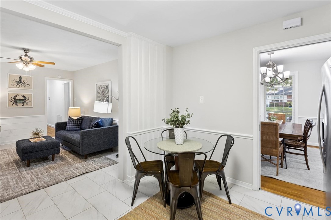 Neutral-toned interior featuring wainscoting, crown molding, and large-format tile flooring