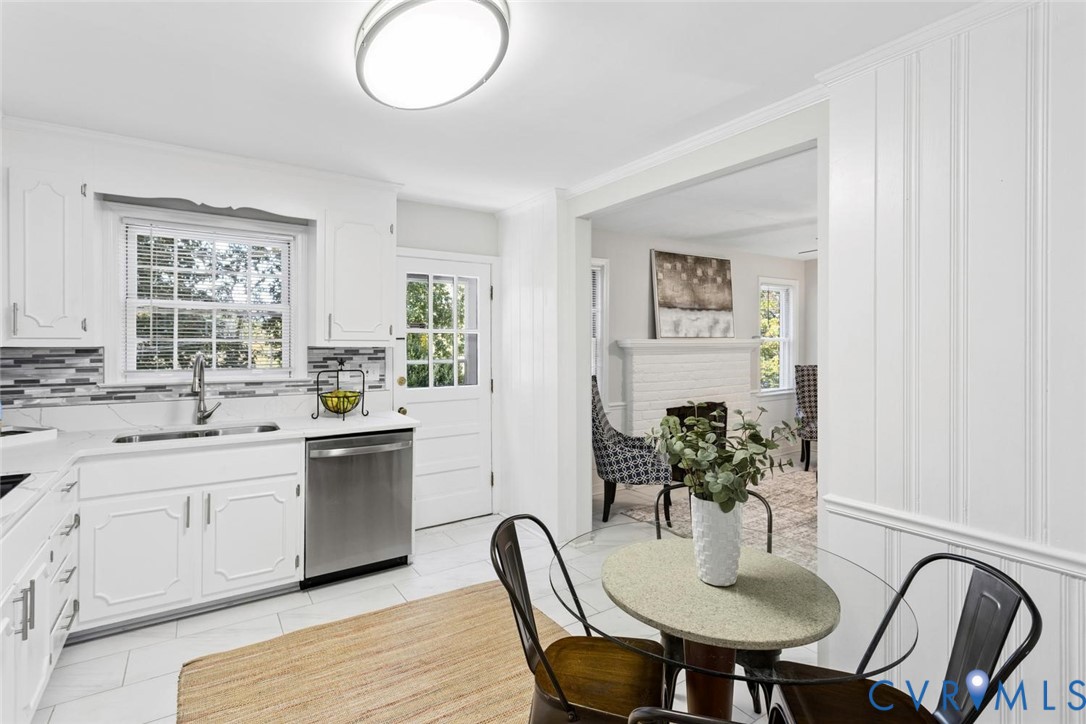 Kitchen featuring white cabinetry, stainless steel dishwasher, tile backsplash, flush-mount lighting, and beadboard wall paneling