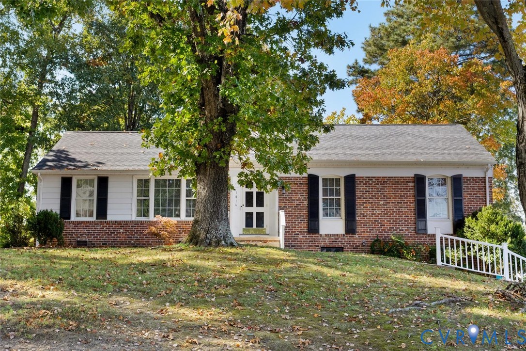 Single-story exterior featuring a brick and siding facade, contrasting window shutters, a shingled roof, and mature landscaping