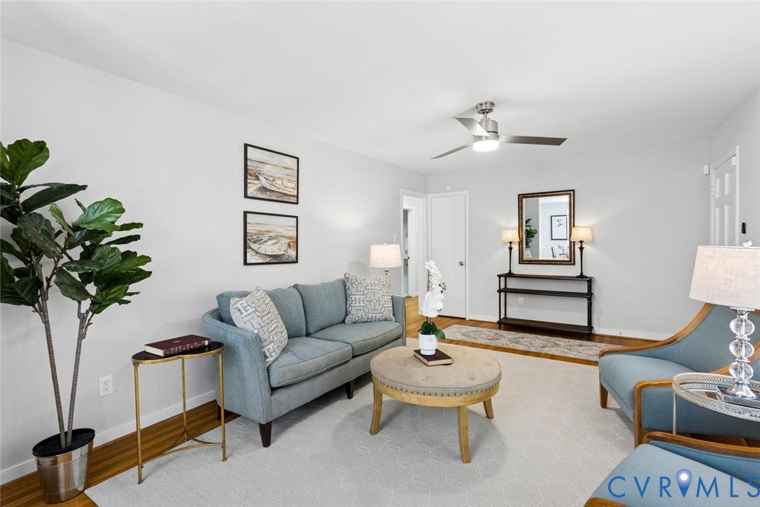 Neutral interior featuring wood-finish flooring, brushed nickel ceiling fan with integrated lighting, and crisp white wall finishes