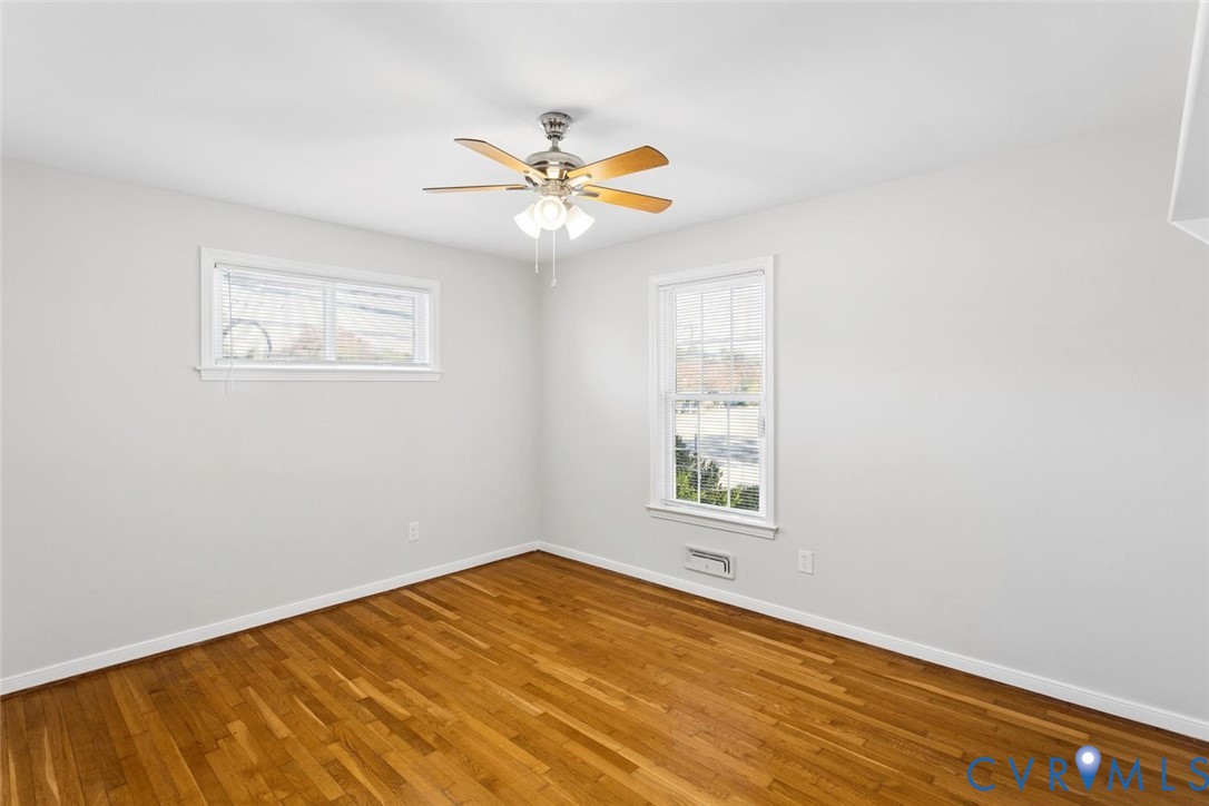 Interior room featuring wood-finish flooring, a multi-blade ceiling fan with integrated lighting, and double-pane windows