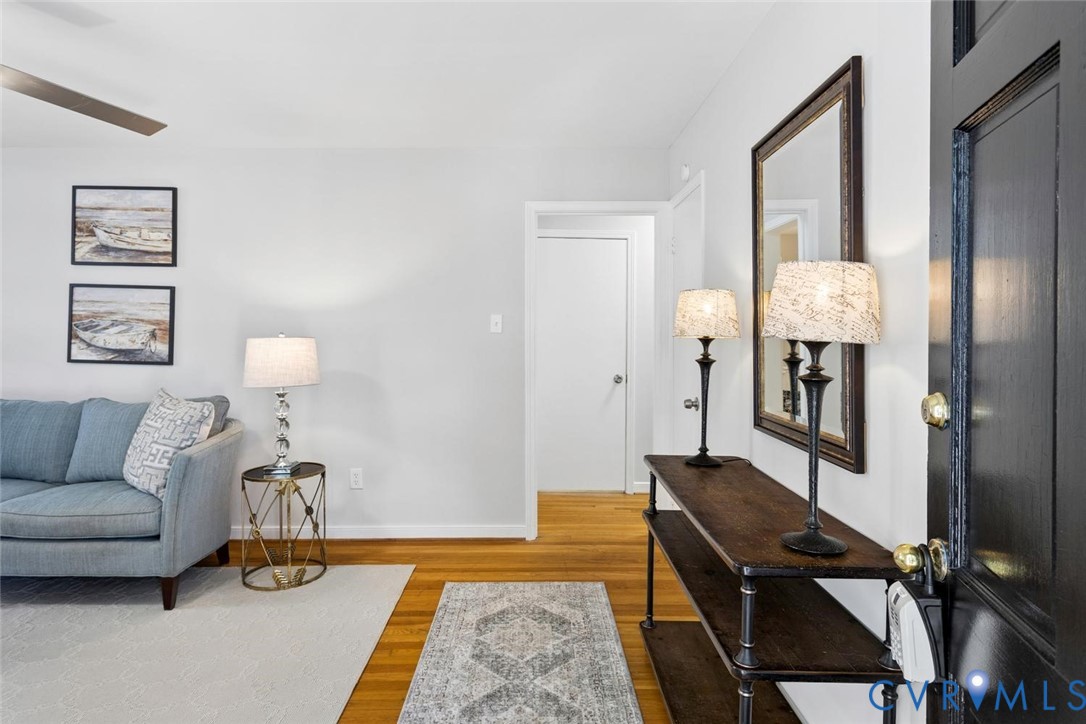 Entryway featuring hardwood flooring, a black-finished door, and a ceiling fan
