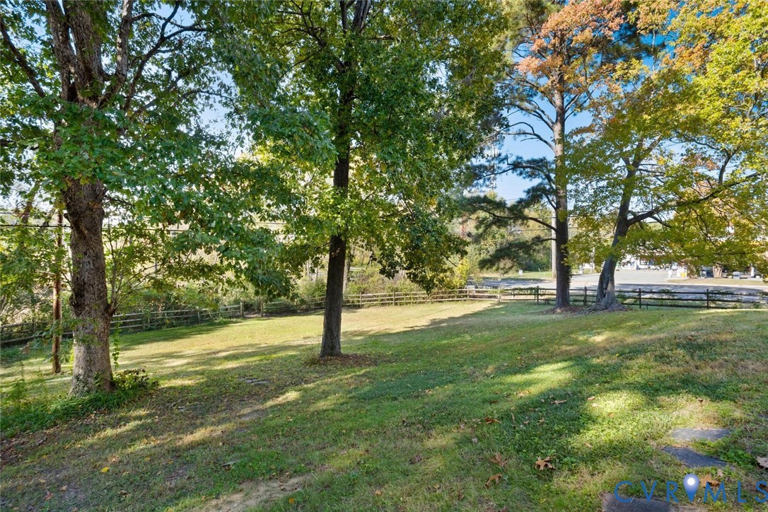 Expansive grassy grounds featuring mature trees and a perimeter split-rail fence
