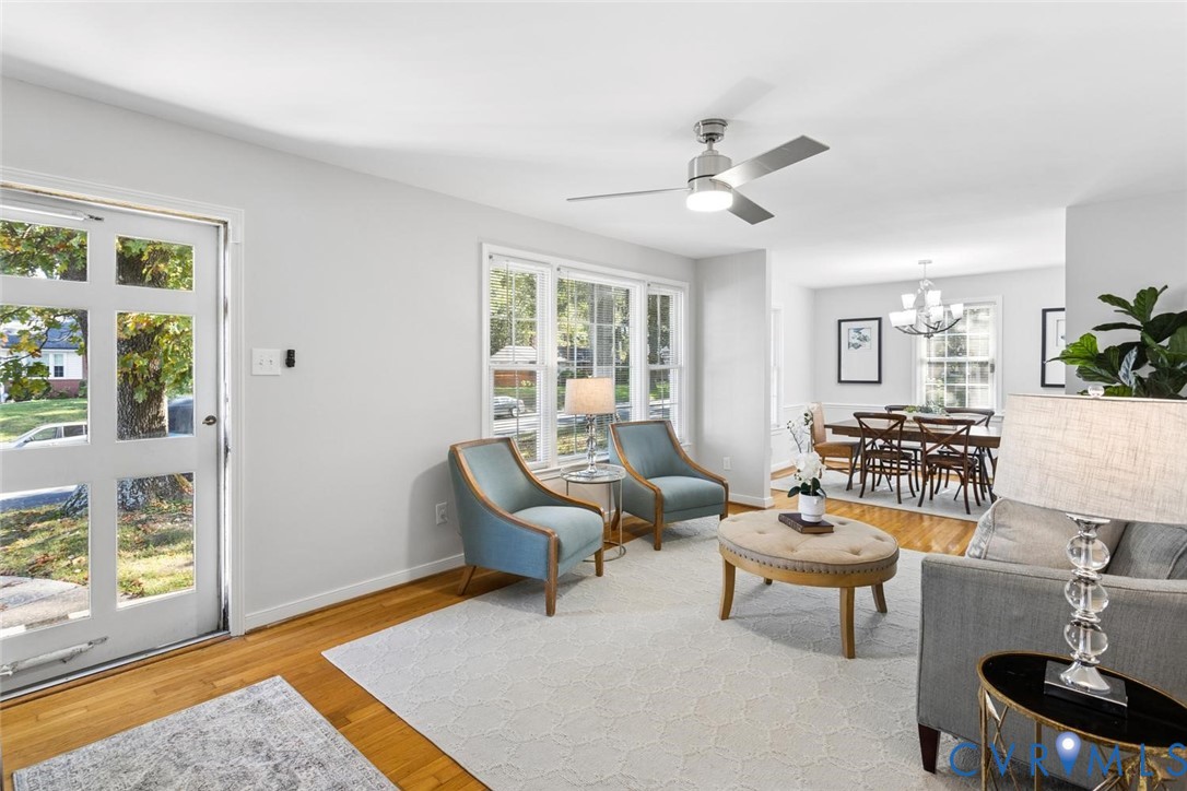 Hardwood flooring, multi-pane entry door, oversized windows, and ceiling fan with integrated lighting