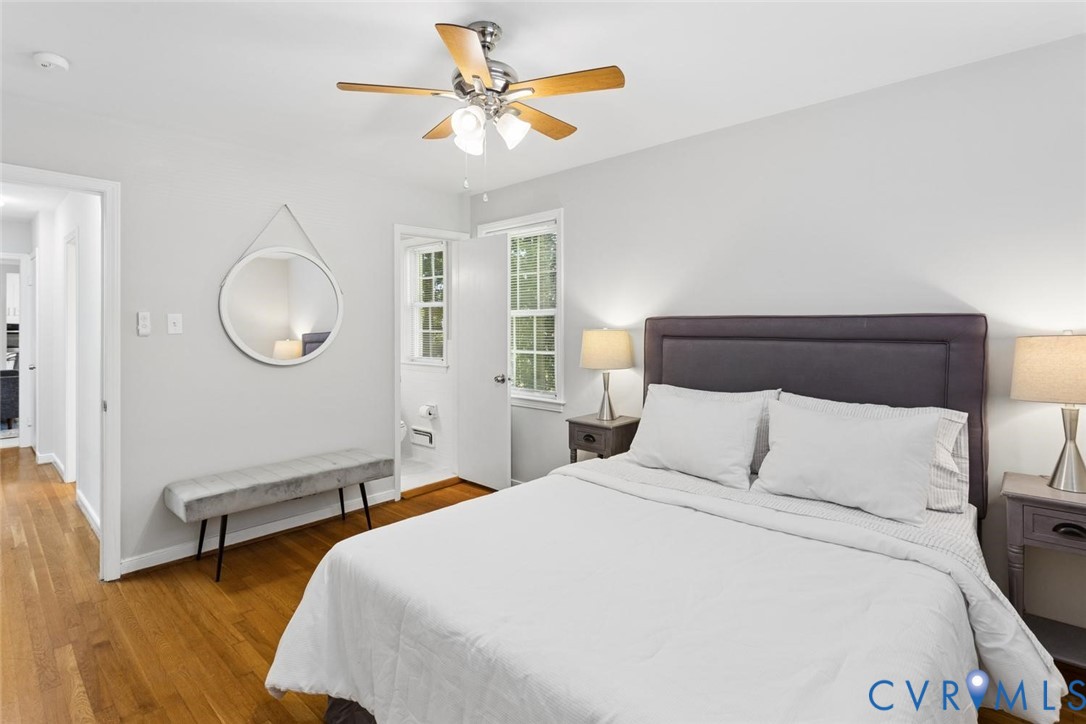 Bedroom featuring wood-finish flooring, a multi-blade ceiling fan with integrated lighting, and double-hung windows
