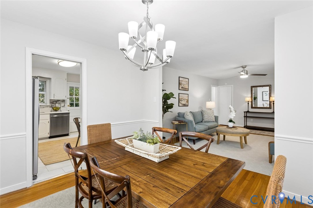Dining area featuring chair rail molding, wood-finish flooring, and a multi-light polished metal chandelier