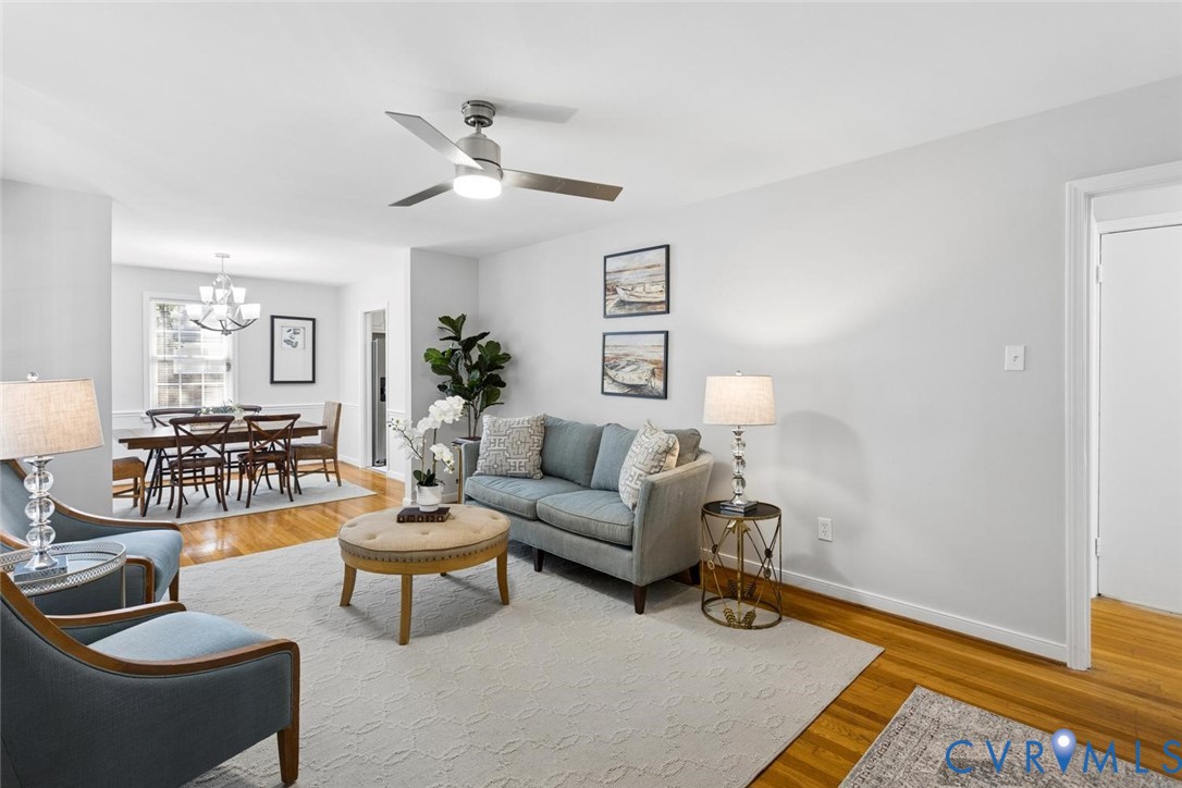 Living space featuring wood-finish flooring, neutral walls, and a modern ceiling fan with integrated lighting