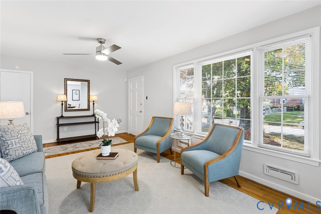 Interior space featuring large multi-pane windows, wood-finish flooring, and a ceiling-mounted light fixture with fan