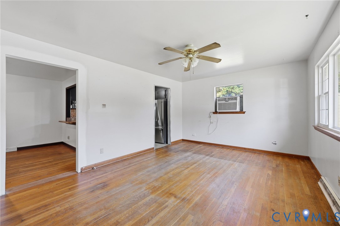 Interior space featuring hardwood flooring, natural light from double-hung windows, and a ceiling-mounted light fixture with a fan