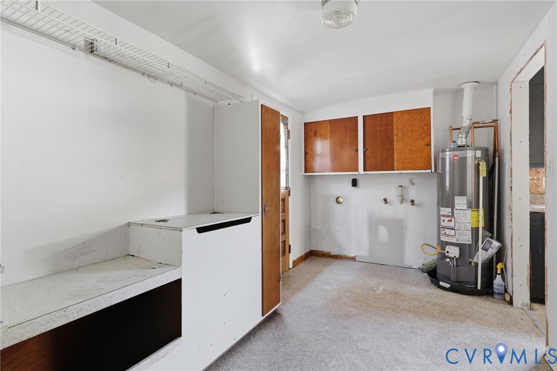 Utility area featuring wood-finish wall-mounted cabinetry, built-in lower storage unit, wire shelving, and an integrated water heater
