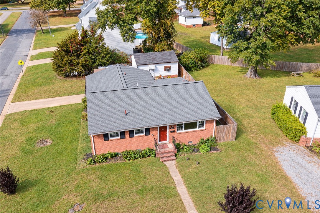 Brick exterior featuring a shingled roof, detached garage, and expansive lawn area