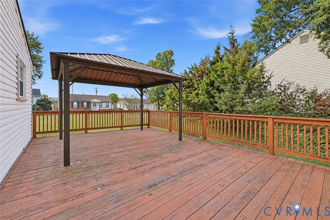 Wood-plank deck featuring a covered metal-roof gazebo and perimeter wooden railings