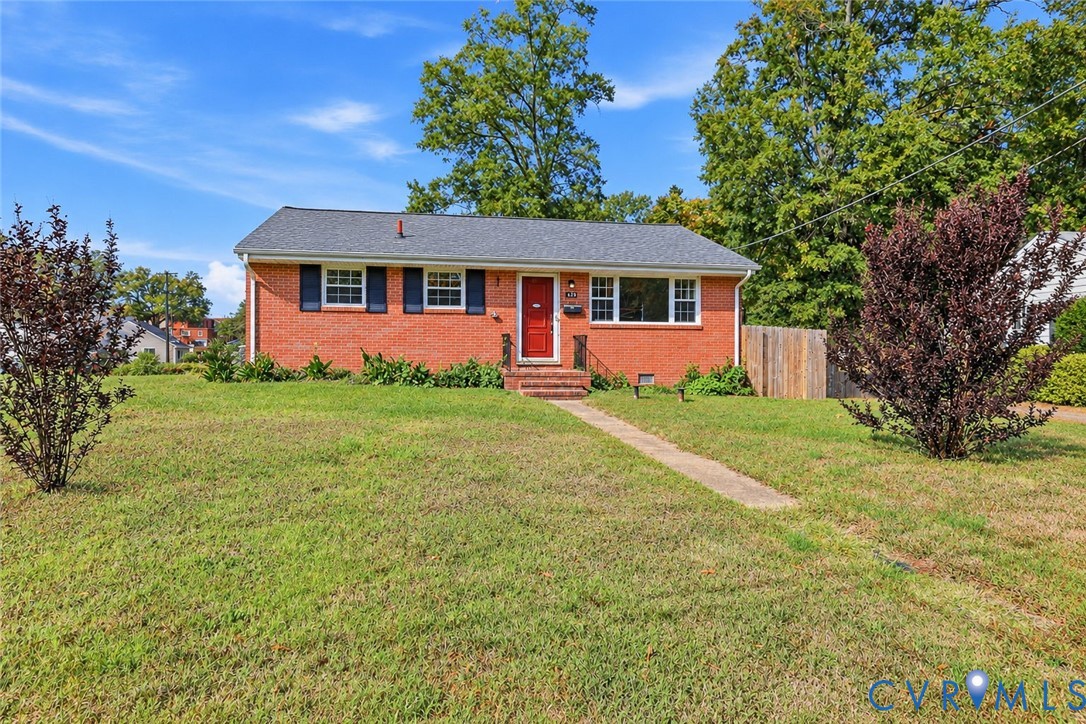 Single-story brick exterior featuring a shingled roof, contrasting dark shutters, and a central red entrance door