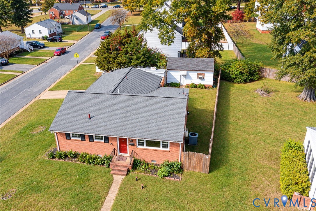 Brick exterior residence featuring a gabled roof, detached storage structure, fenced yard, and professional landscaping