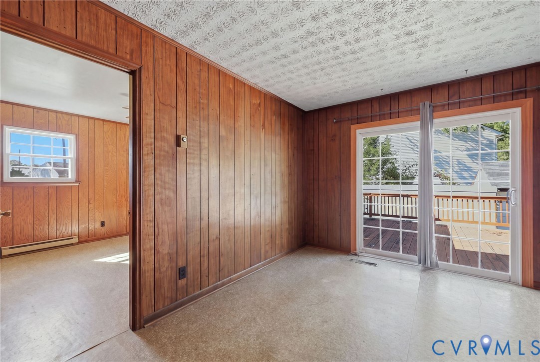 Wood-panelled interior walls, sliding glass door with grid muntins, and access to an exterior deck