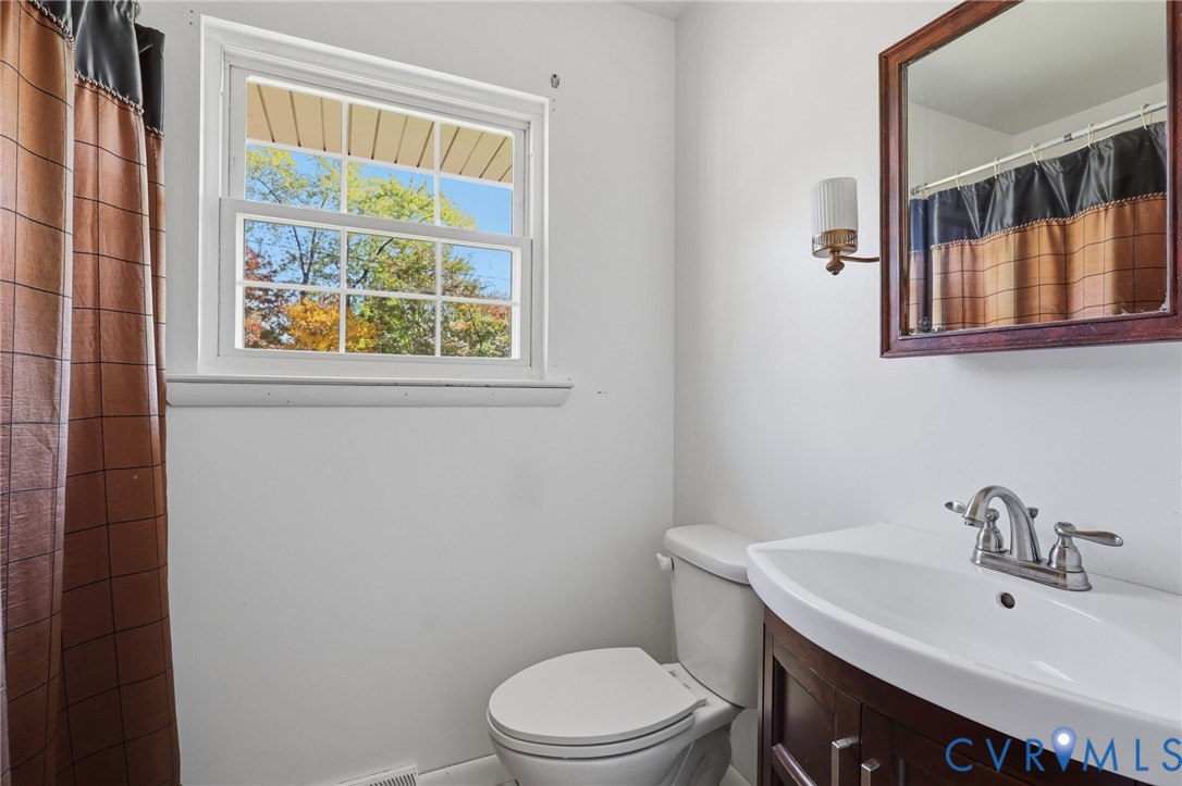 Bathroom featuring a dark-finish vanity with a white integrated sink, polished chrome faucet, wooden-framed mirror, and a double-hung window