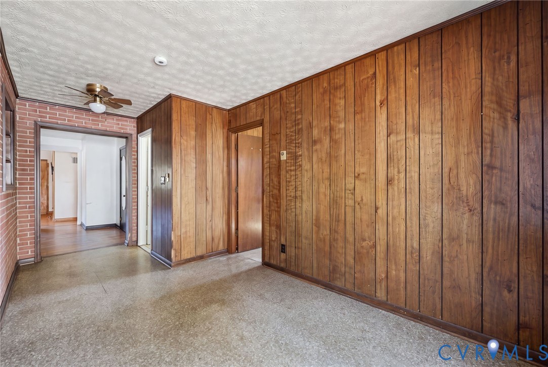 Interior space featuring vertical wood-panelled walls, exposed brick accents, and a ceiling-mounted fan