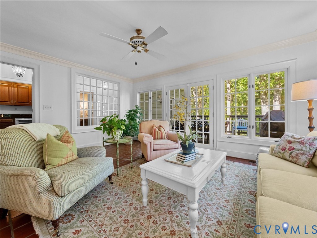 Sunroom featuring tile flooring, crown molding, a ceiling fan, grid-pattern windows, and French doors