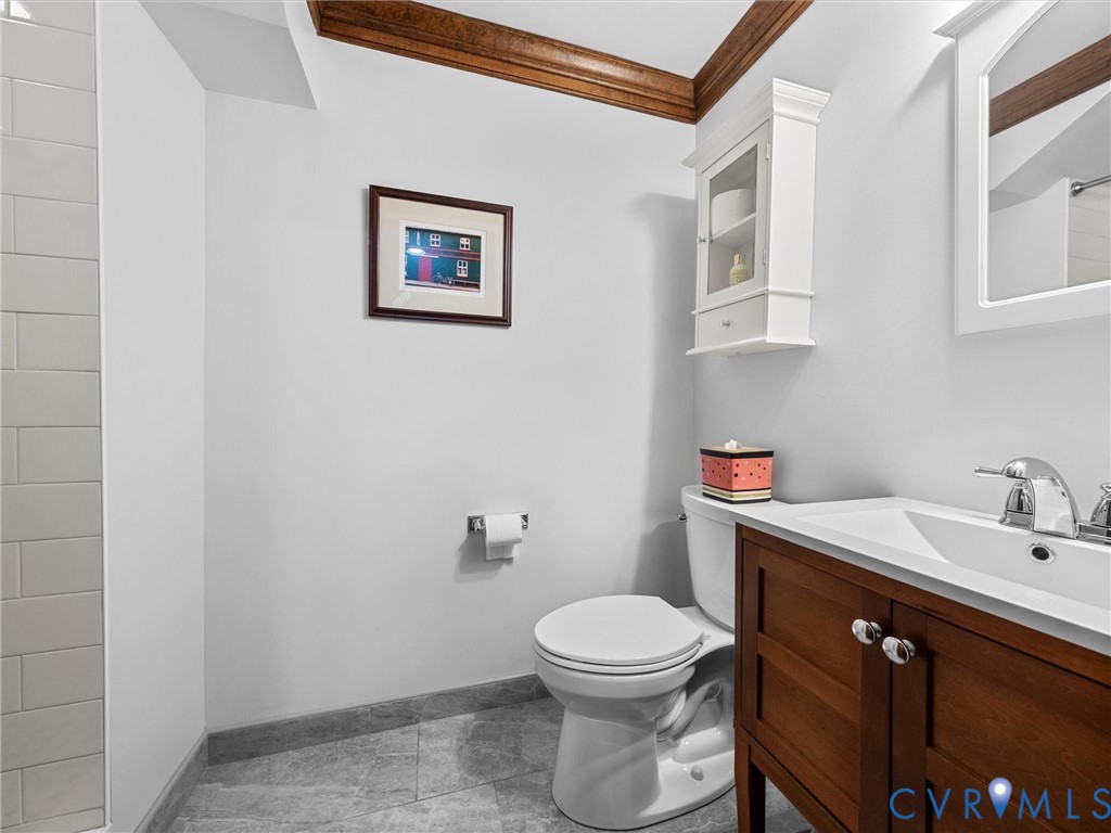 Bathroom featuring stone-tile flooring, subway-tiled wall, vanity with wood cabinetry, and white wall-mounted storage cabinet