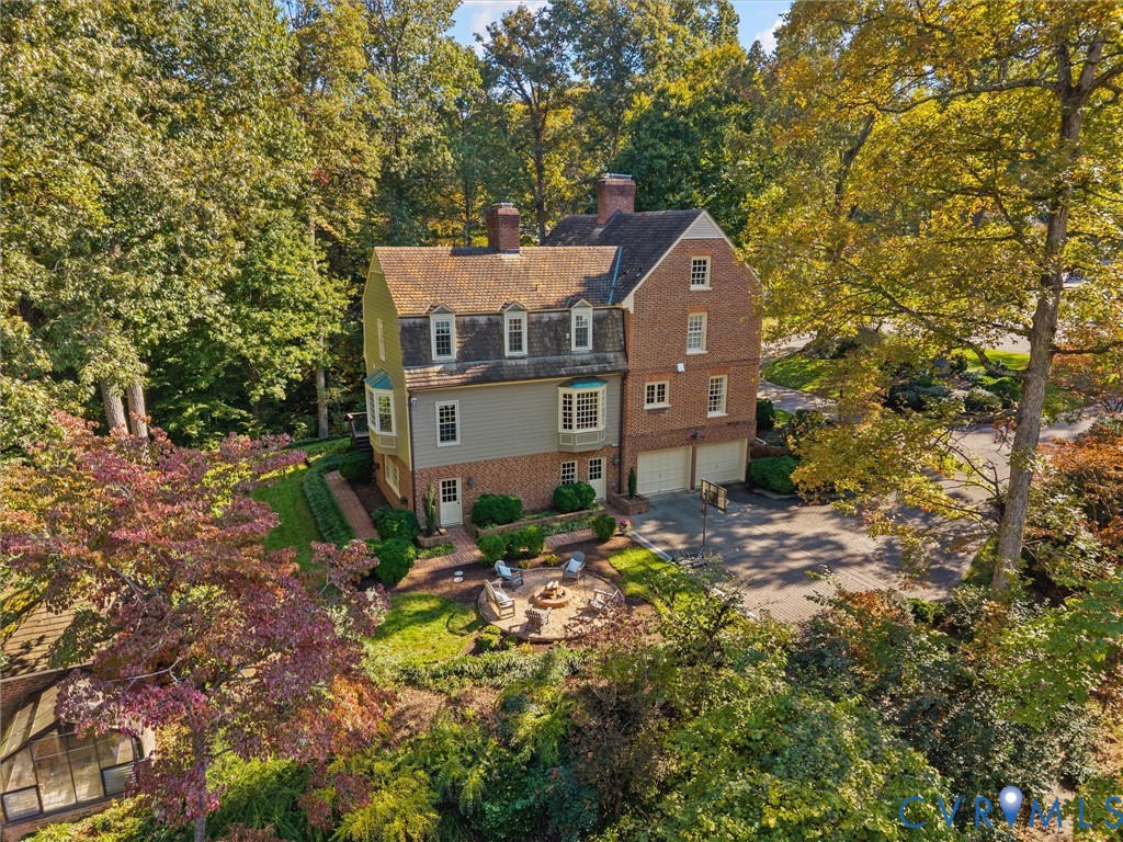 Multi-story residence featuring a brick and siding exterior, dual chimneys, multiple dormer windows, bay windows, and an attached two-car garage
